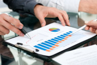 two pair of hands pointing on the histogram graph on a paper